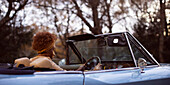 Young woman driving convertible in park