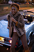 Happy young woman outside convertible