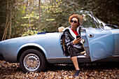 Young woman with smartphone in convertible in park