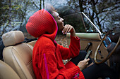 Carefree young woman with smartphone in convertible