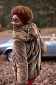 Happy young woman in fur coat in park