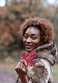 Happy young woman with red autumn leaf