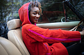 Happy stylish young woman driving convertible