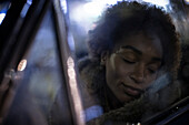 Serene young woman with eyes closed in car window
