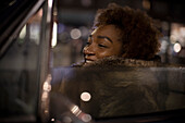 Young woman in fur coat driving convertible at night