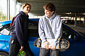 Happy teenage boys with skateboards in parking garage