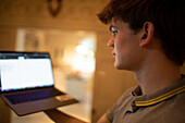 Teenage boy using laptop at home