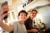 Happy teenage boys taking selfie and cooking in kitchen
