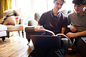 Teenage boys with textbook and laptop studying at home