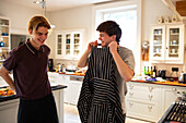 Happy teenage boys with apron cooking in kitchen