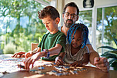 Father and kids assembling jigsaw puzzle at home