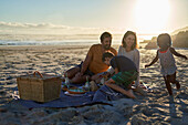 Happy family enjoying picnic on sunny summer beach