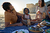 Toddler girl enjoying picnic with family on beach