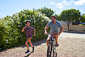 Happy father and son running and riding bike in driveway