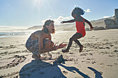 Mother and playful toddler daughter on sunny summer beach