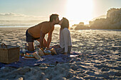 Affectionate couple kissing on picnic blanket on beach