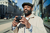 Male tourist using digital camera on city sidewalk
