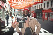 Woman in face mask photographing happy man