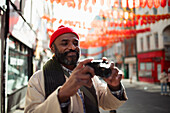 Male tourist with digital camera, Chinatown, London, UK