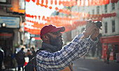 Male tourist using digital camera in sunny city