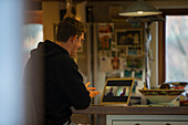 Man video conferencing with colleagues on laptop in kitchen