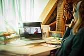 Woman video conferencing with colleagues on laptop screen