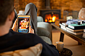 Man looking at takeout menu on digital tablet in living room