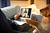 Man with dog video conferencing with colleagues