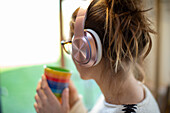 Woman with coffee listening to music on headphones