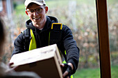 Friendly male courier delivering package at front door