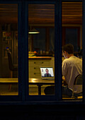 Man working late video conferencing with colleagues