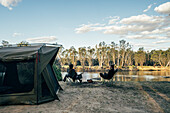 Couple relaxing outside tent at lake in Australian bush