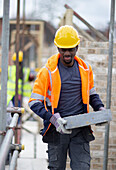 Construction worker carrying brick at construction site