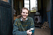 Happy young man drinking coffee in cabin doorway