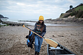Young woman with oars at canoe on winter beach