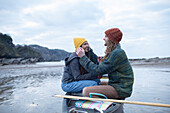 Happy young couple in canoe on ocean surf