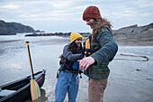 Young couple preparing for canoeing on ocean beach