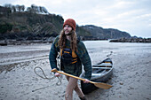 Young man with canoe and oar on beach