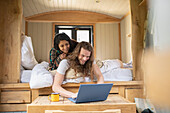 Happy young couple using laptop in tiny cabin bed