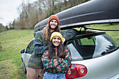 Happy young couple outside car with canoe on top