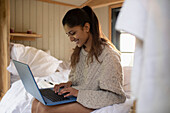 Young woman using laptop in bed