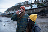 Young couple drinking wine on winter beach