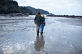 Affectionate young couple walking on wet sand beach
