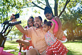 Grandfather and granddaughters taking selfie in park