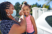 Mother helping cute toddler daughter with face mask