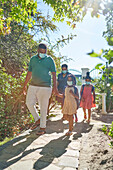 Family in face masks on sunny summer footpath