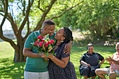Happy couple with rose bouquet in park