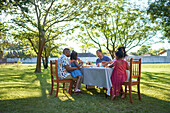 Multigenerational family enjoying lunch at table in backyard
