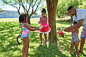 Father and daughters playing with water squirt gun