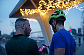 Men with smartphone under illuminated bridge at night